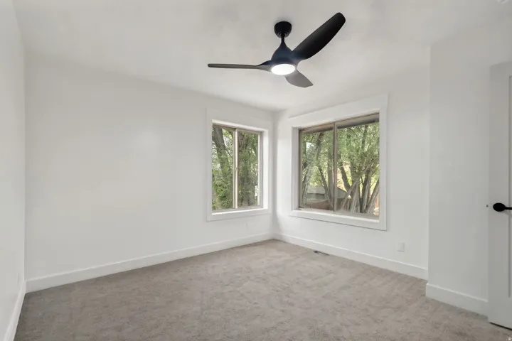Interior room with light gray carpeting, crisp white walls, and two large windows featuring white trim