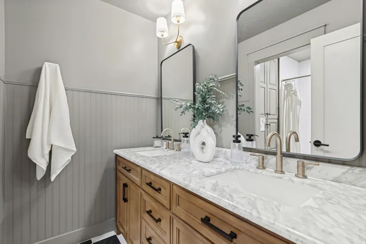 Double vanity featuring a light wood-finish cabinet with dark hardware, a white stone countertop, and two undermount sinks