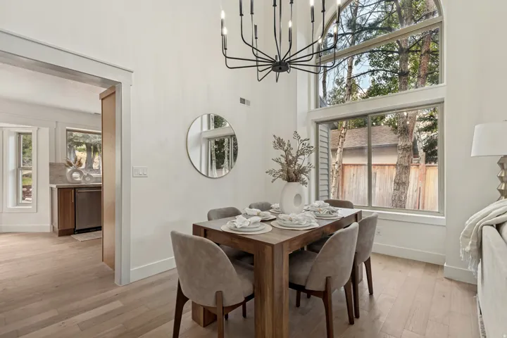 Dining area featuring a soaring ceiling, expansive windows, light wood-finish flooring, and a modern chandelier