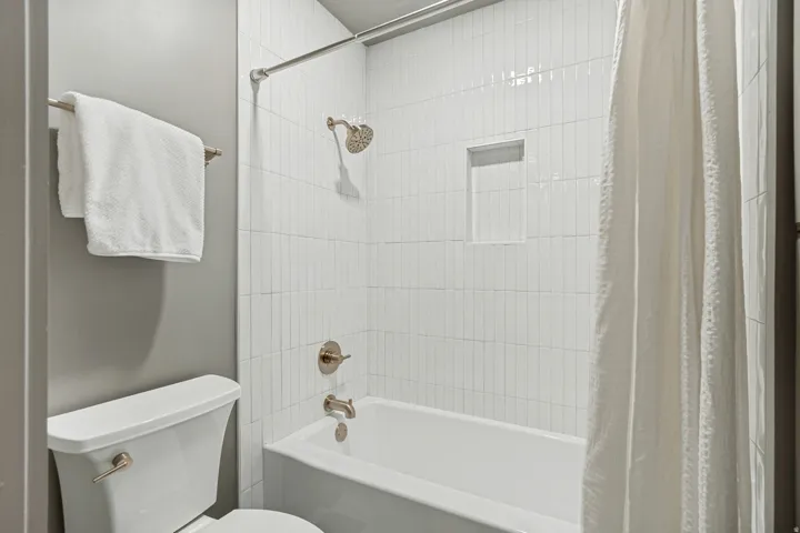 Full bathroom featuring a tub/shower combination with vertical subway tile surround, recessed shower niche, and brushed nickel fixtures