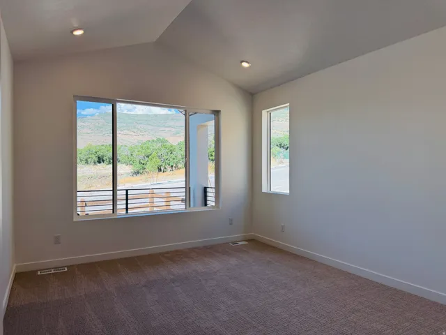 Spacious room featuring vaulted ceilings with recessed lighting, large windows, and neutral carpeting