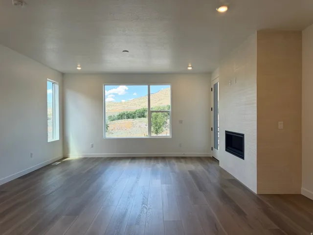 Spacious room featuring wood-finish flooring, recessed lighting, and large windows showcasing a mountain backdrop
