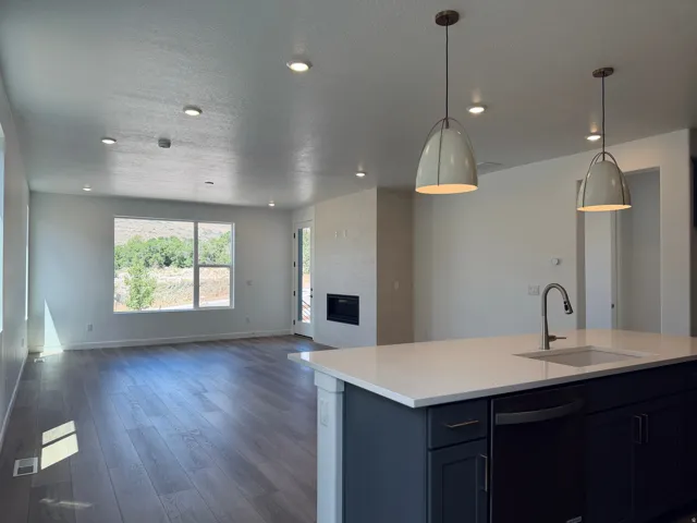 Kitchen island with quartz countertop and undermount sink, accented by two pendant lights