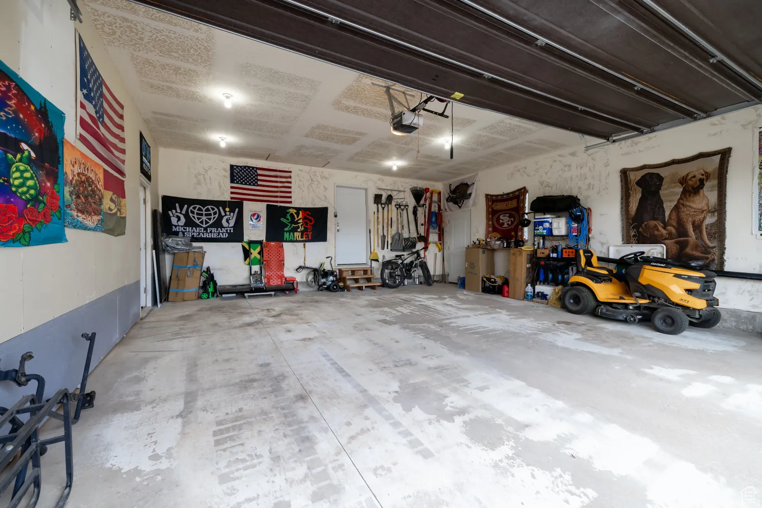 Spacious garage featuring concrete flooring, an automatic overhead door, and multiple ceiling-mounted light fixtures