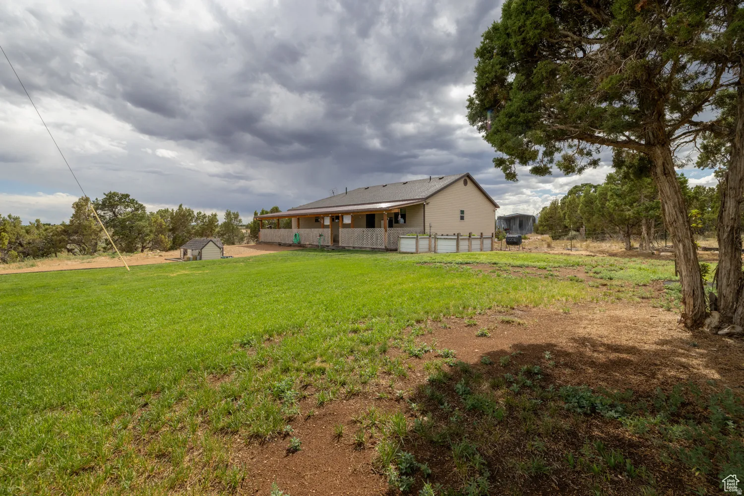 Spacious grounds featuring a detached shed, covered porch, and mature trees