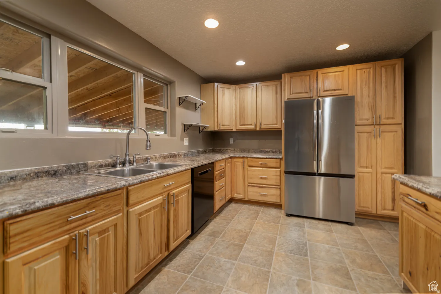 Kitchen featuring natural wood cabinetry, light-toned countertops, and a double basin stainless steel sink