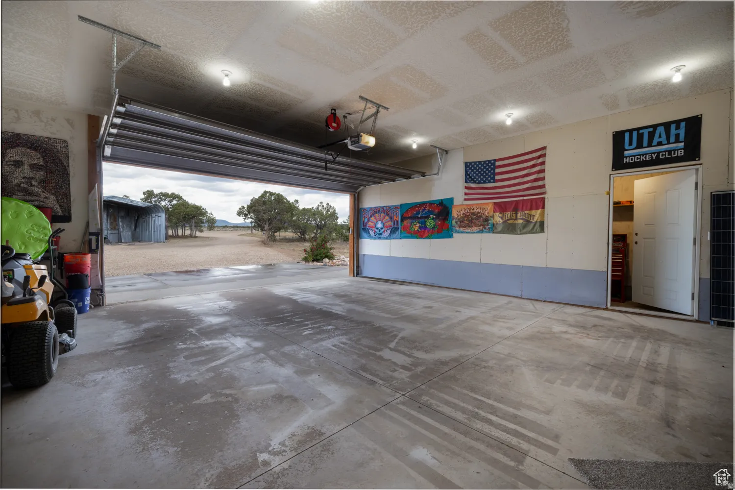 Spacious garage featuring a concrete floor, overhead garage door, built-in lighting, and an additional access door