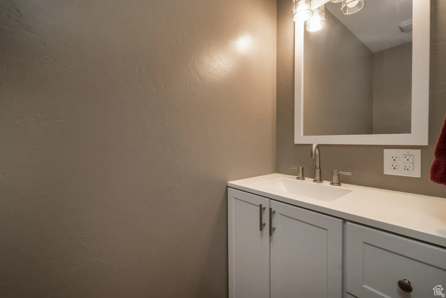 Bathroom vanity with white cabinetry, integrated sink, and brushed nickel fixtures