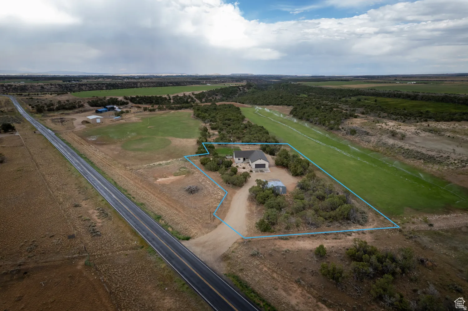 Expansive property featuring a single-story residence with an attached two-car garage, a long private driveway, and mature landscaping