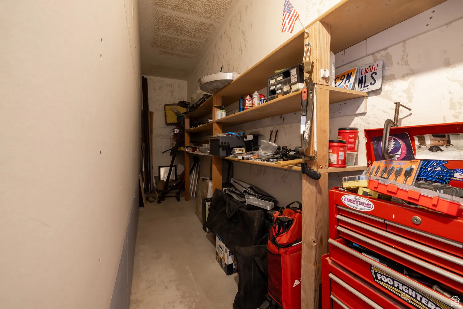 Utility room featuring built-in wood shelving, concrete flooring, and ample storage space