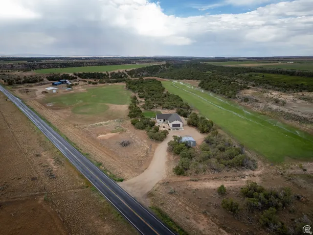 Expansive property featuring a single-story residence with an attached garage, a private airstrip with irrigation, multiple outbuildings, and a paved road frontage