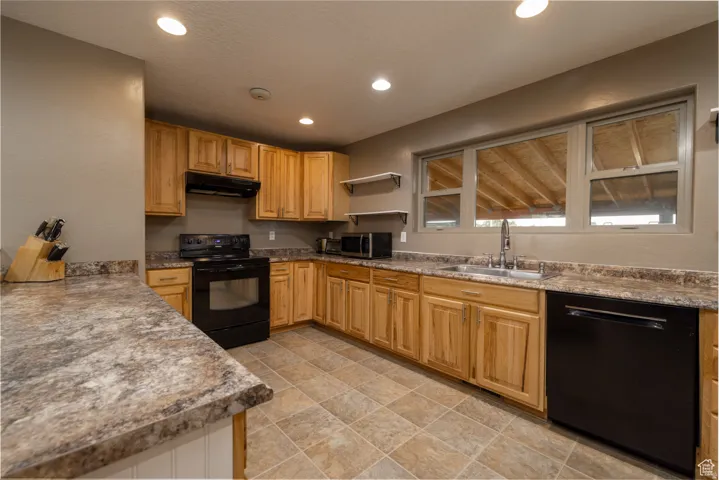 Kitchen featuring light wood cabinetry, stone-finish countertops, and tile flooring