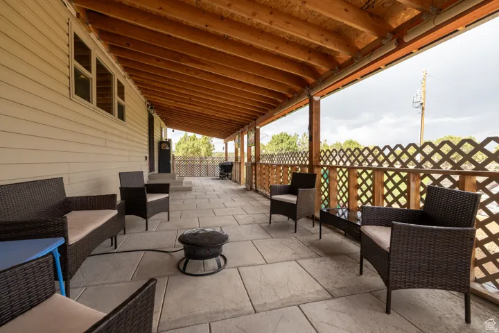 Expansive covered patio featuring a wood-beam ceiling, lattice railing, and a stone paver surface