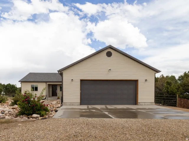 Gravel driveway leading to a two-car garage with a dark gray door