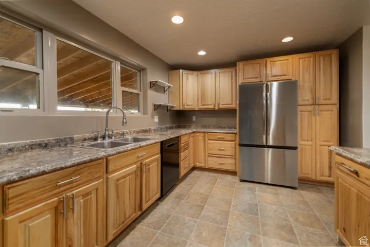 Kitchen featuring natural wood cabinetry, light-toned countertops, and a double basin stainless steel sink