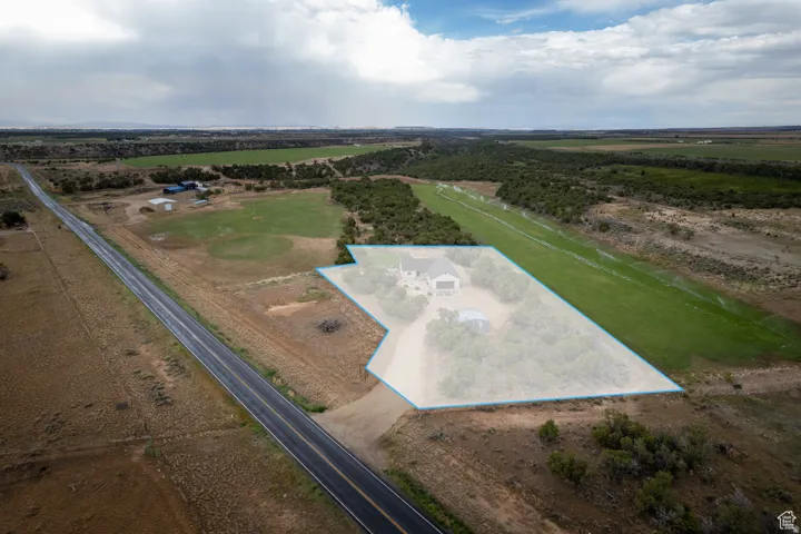 Aerial perspective highlighting a substantial land parcel with a single-family residence, an additional structure, and a dedicated airstrip