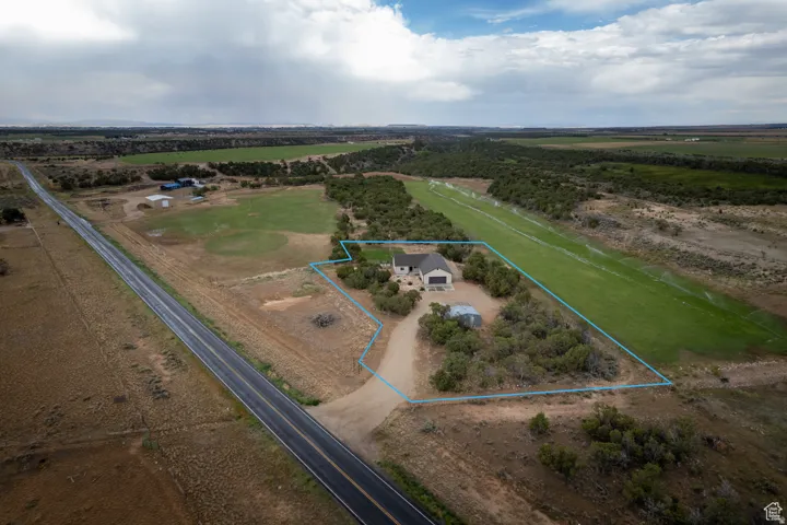 Expansive property featuring a single-story residence with an attached two-car garage, a long private driveway, and mature landscaping
