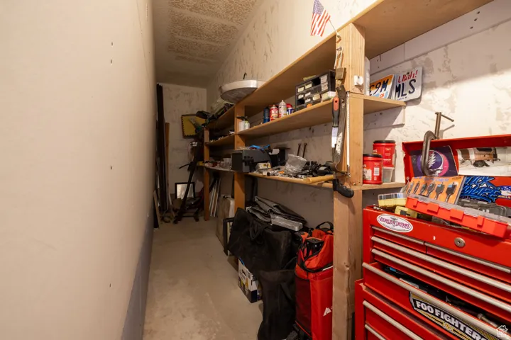 Utility room featuring built-in wood shelving, concrete flooring, and ample storage space