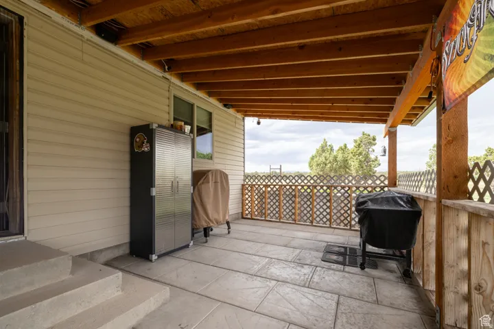Covered patio featuring a wood-beam ceiling, stamped concrete flooring, and lattice railing