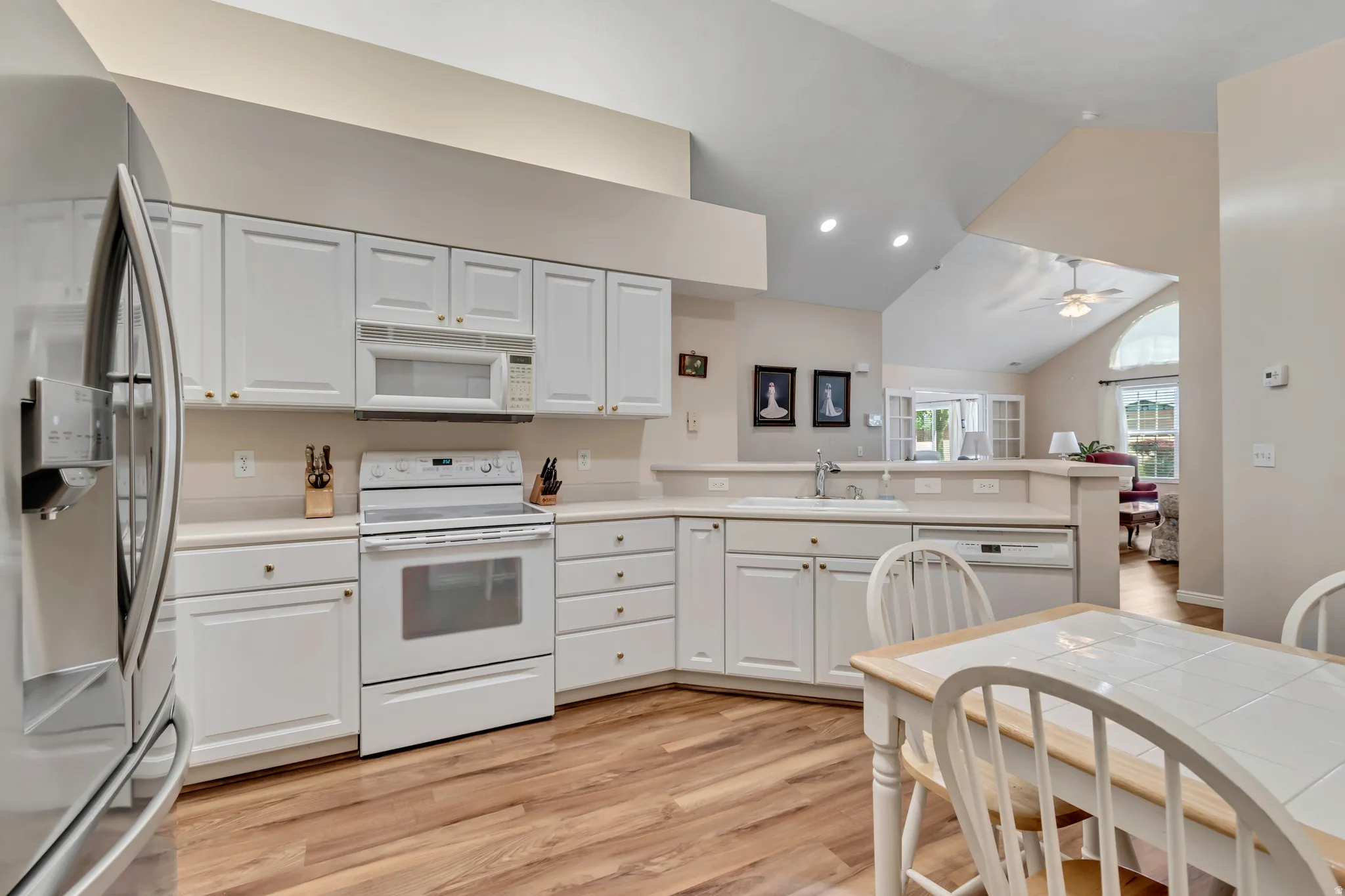 Kitchen featuring white cabinetry, light countertops, wood-finish flooring, and stainless steel appliances including a refrigerator, range, microwave, and dishwasher