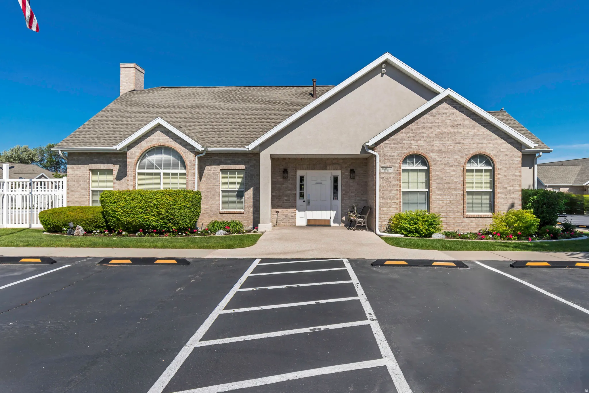 Traditional-style building featuring a brick and stucco exterior, gabled roofline, arched windows, and a dedicated parking area