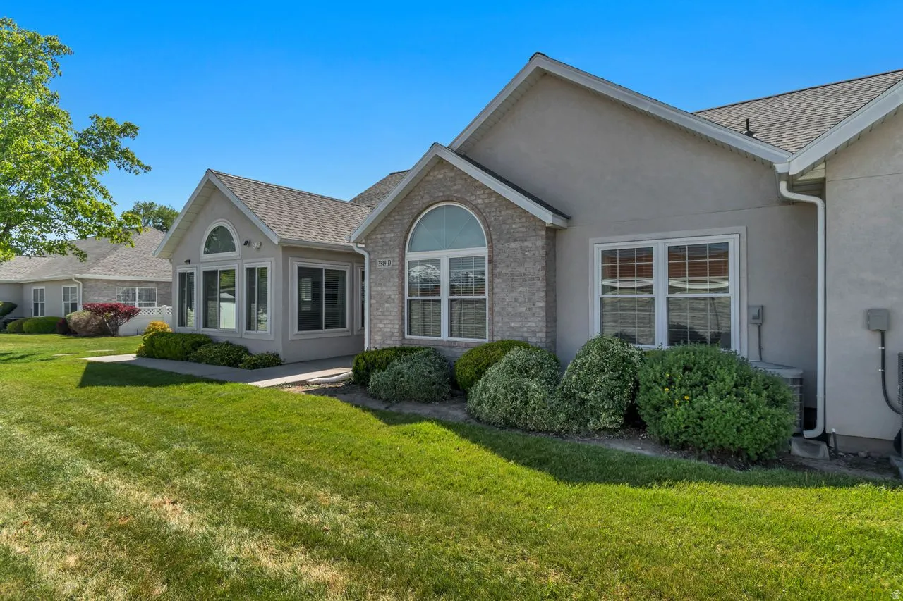 Stucco and brick exterior featuring multiple arched windows, a sunroom extension, and a gabled roofline