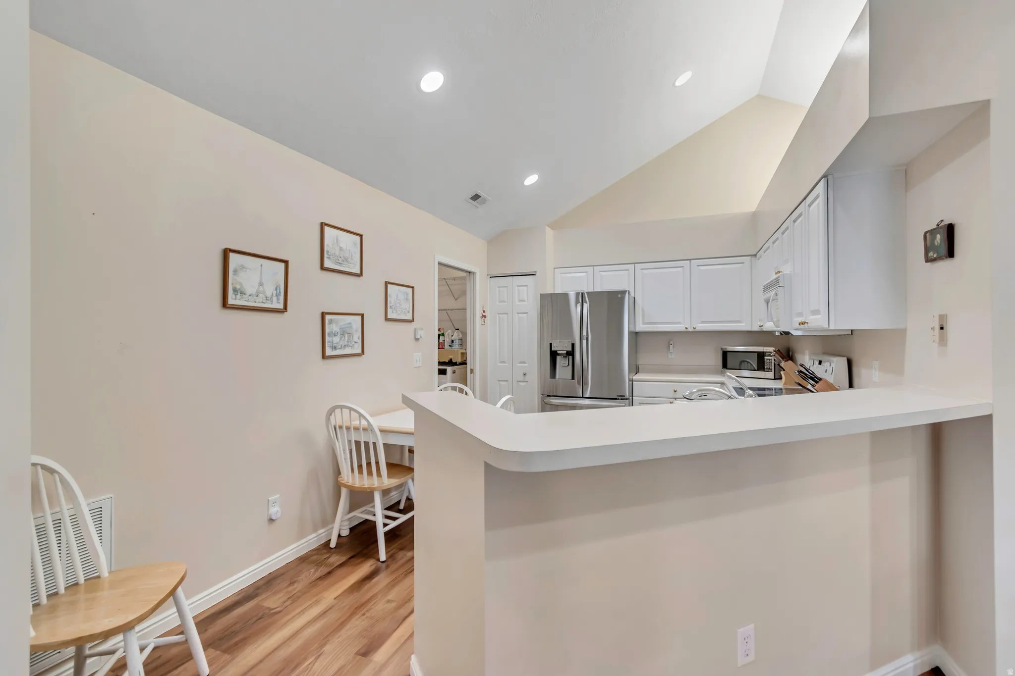 Modern kitchen featuring stainless steel appliances, white cabinetry with soft-close doors, quartz countertops, and a curved island with breakfast bar seating