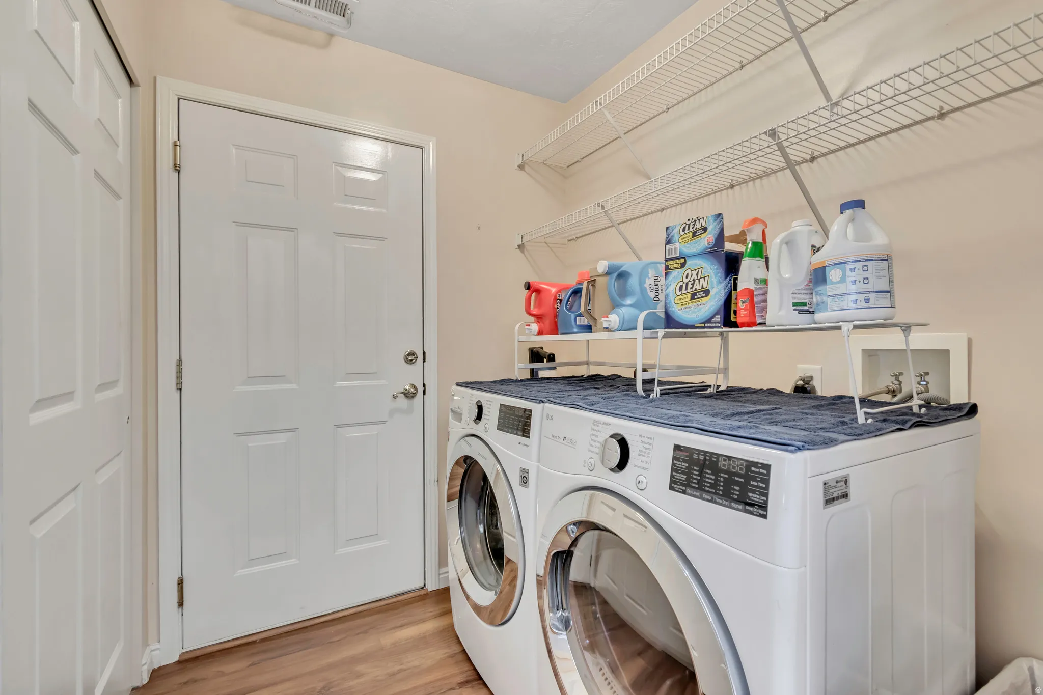 Laundry area featuring wood-finish flooring, white paneled doors, and wall-mounted wire shelving
