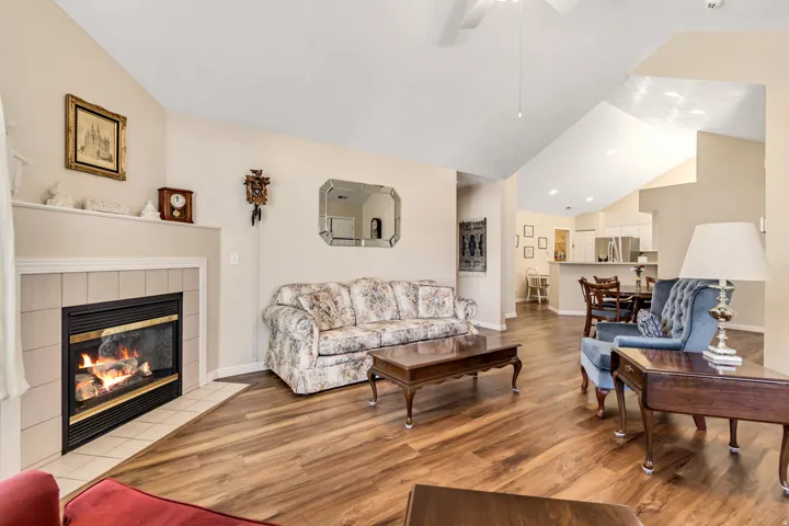 Living area featuring vaulted ceilings, wood-finish flooring, and a tile-surround fireplace