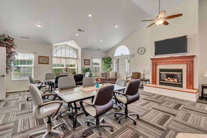 Spacious common area featuring a vaulted ceiling, a gas fireplace with a wood mantle, an arched transom window, recessed lighting, and patterned carpet flooring