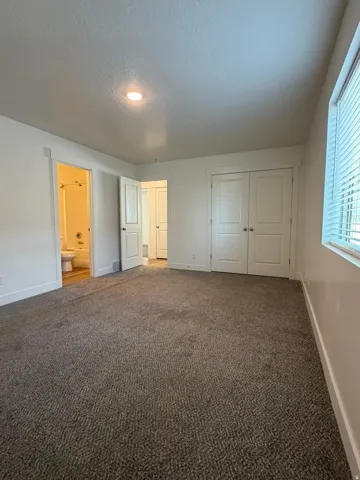 Carpeted room featuring a ceiling-mounted light fixture, white walls, and white trim