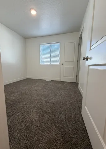 Room featuring neutral-toned carpet flooring, white walls, and a window with horizontal blinds