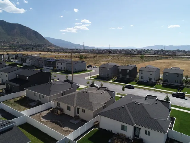 New construction residential development featuring modern homes with dark asphalt shingle roofs and light-colored siding