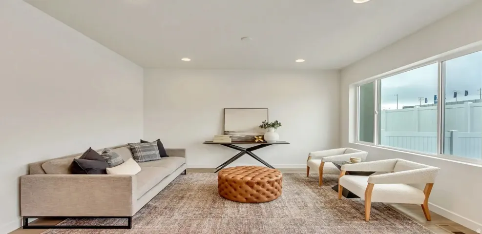 Spacious living area featuring light-toned walls, recessed lighting, and large windows providing ample illumination.Picture is of a similar home.