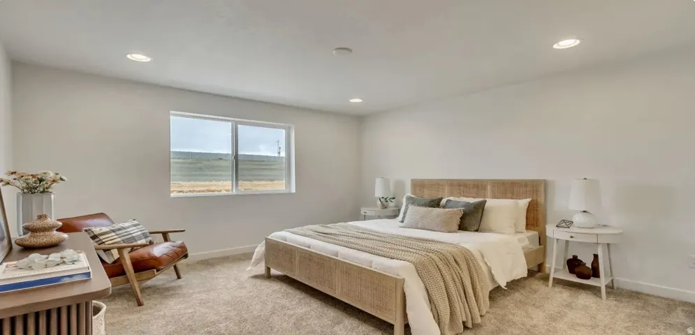 Carpeted bedroom featuring white walls, a large window, and recessed lighting. Picture is of a similar home.