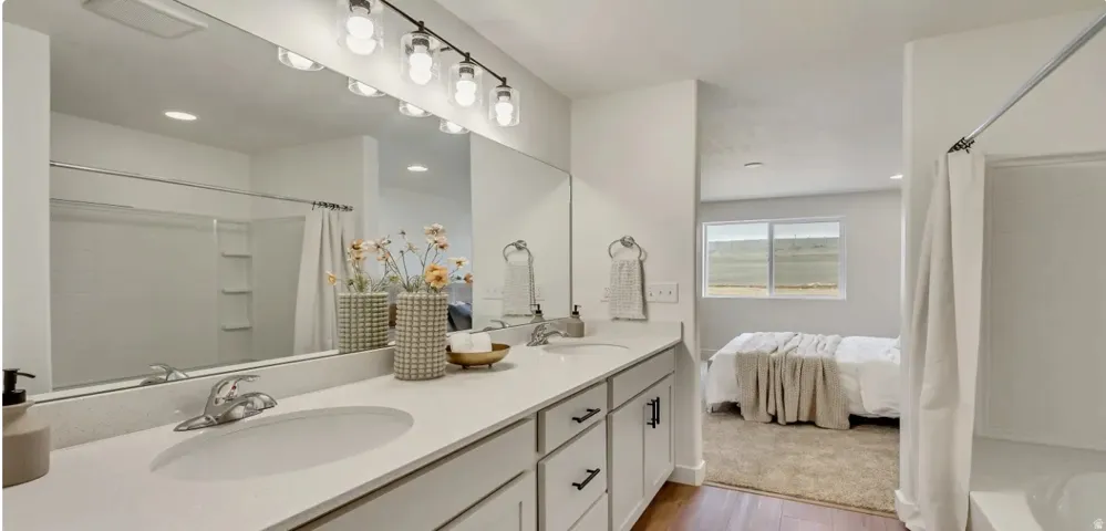Dual vanity with a white quartz-finish countertop, undermount sinks, and light gray cabinetry.  Picture is of a similar home.
