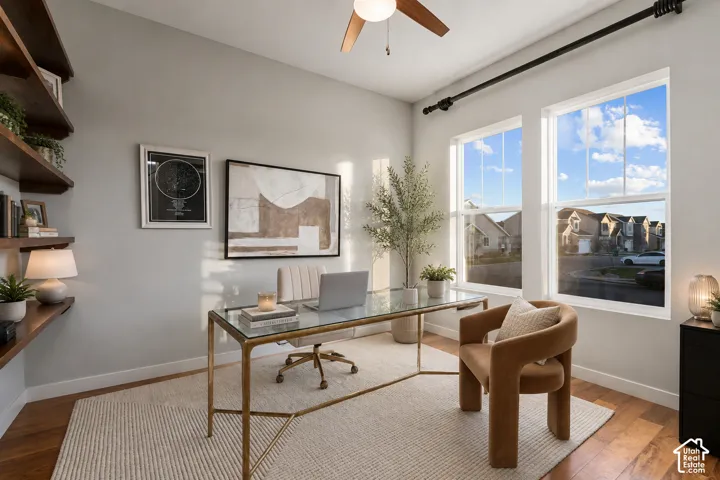 Hardwood flooring with a matte finish, built-in shelving, dual-pane windows, and a ceiling fan with light fixture