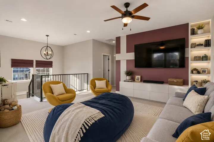 Built-in shelving with integrated lighting, wood-finish ceiling fan, recessed lighting, white built-in media console, and black metal railing