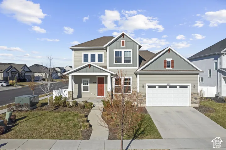 Two-story residence featuring a two-car garage, stone accents on the facade, a covered front porch, and a red entry door