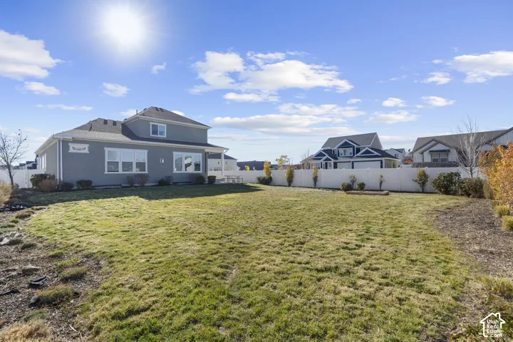 Expansive grassy yard with a privacy fence and established trees