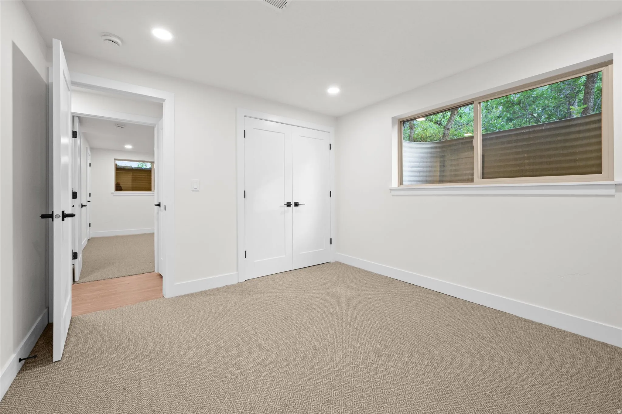 Carpeted room with a horizontal window featuring a window well