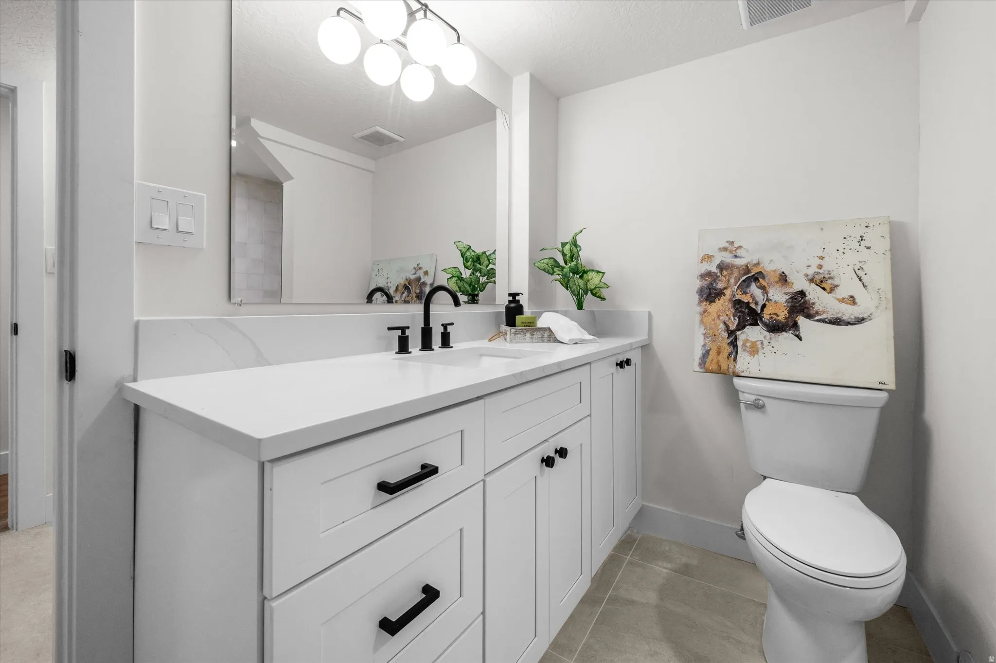 Bathroom featuring a white vanity with shaker-style cabinetry, black hardware, and a white countertop