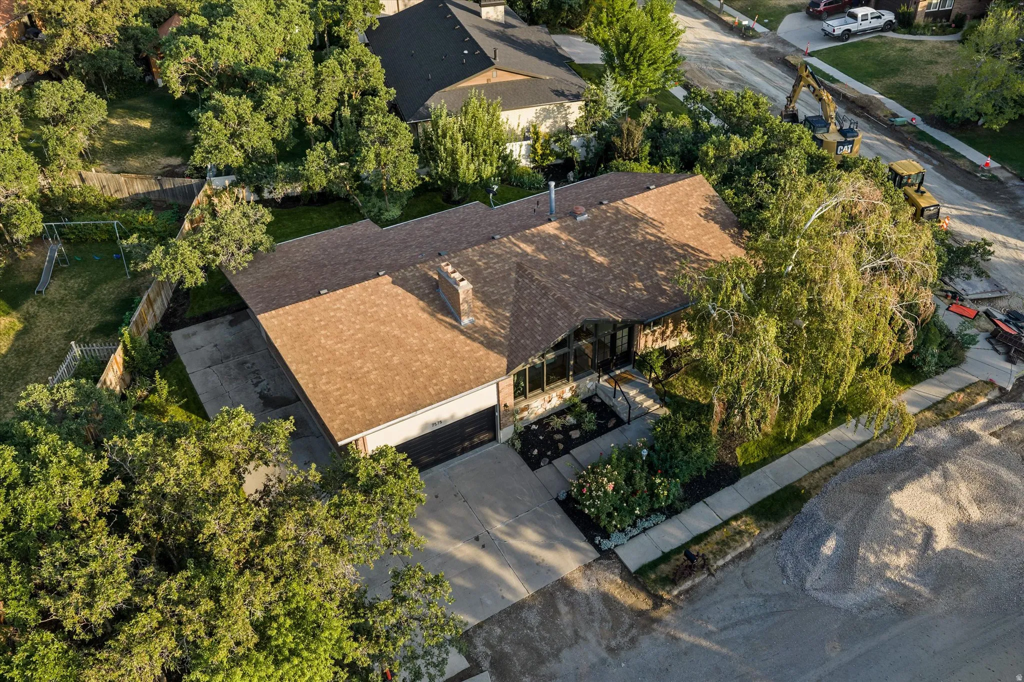 Ranch-style residence featuring a brown shingle roof and a prominent stone chimney