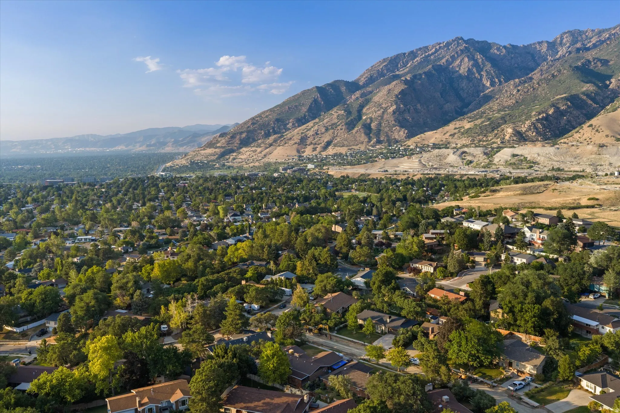 Expansive mountain scenery with a lush valley of mature trees and residential properties
