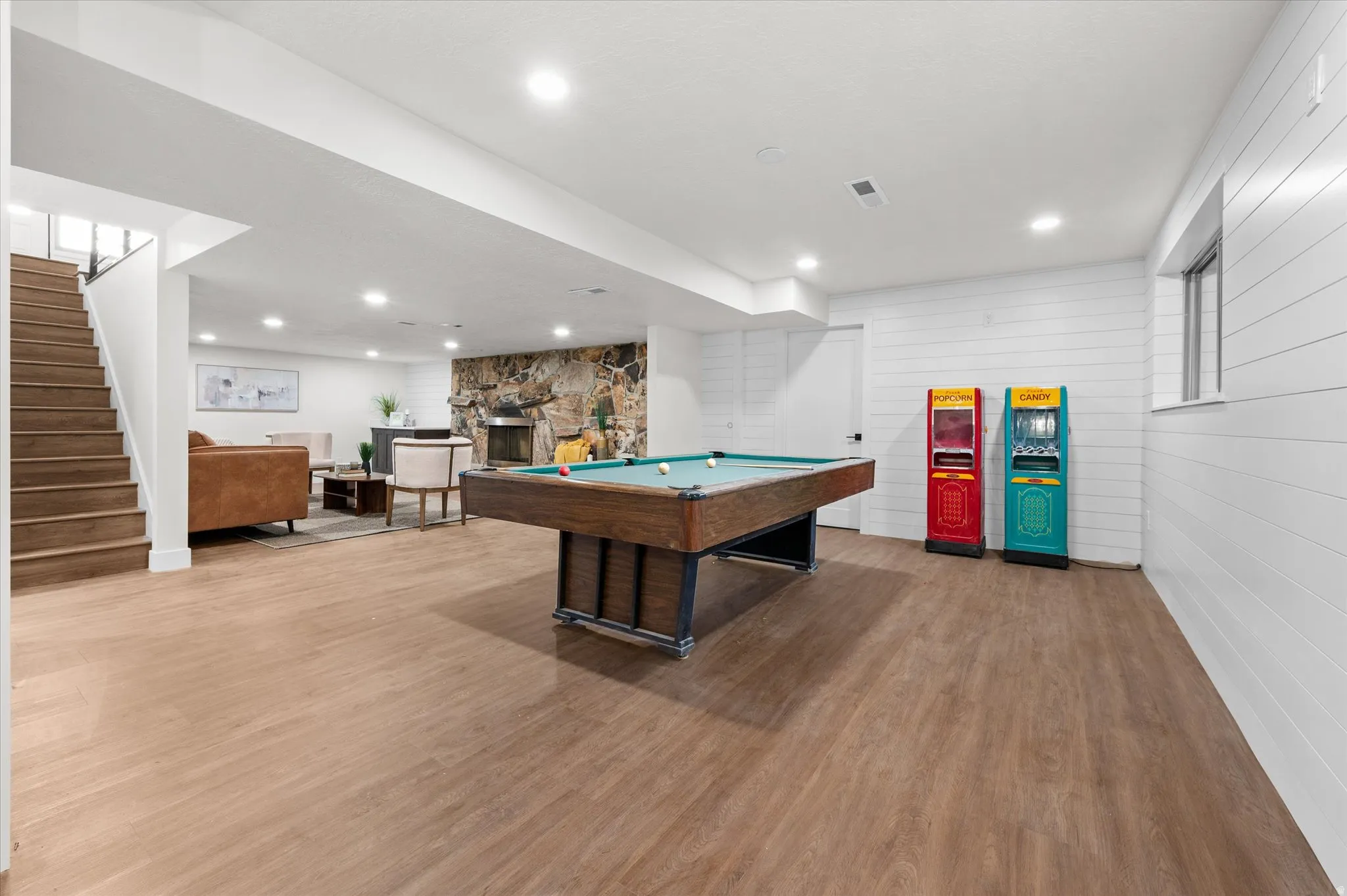 Expansive finished basement featuring wood-finish flooring, recessed lighting, and white shiplap accent walls