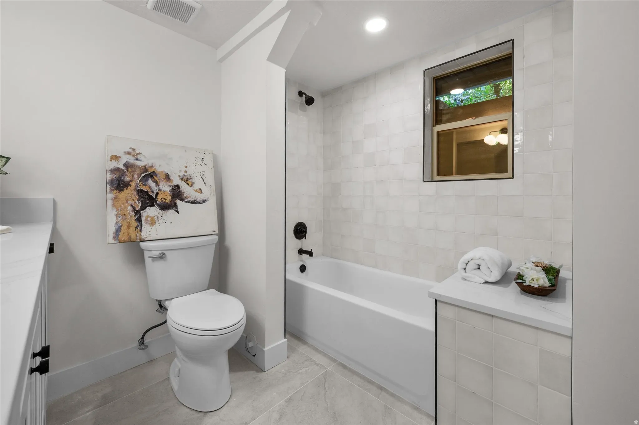 Bathroom featuring a windowed shower-tub combination, matte black fixtures, and light-toned tile surrounds