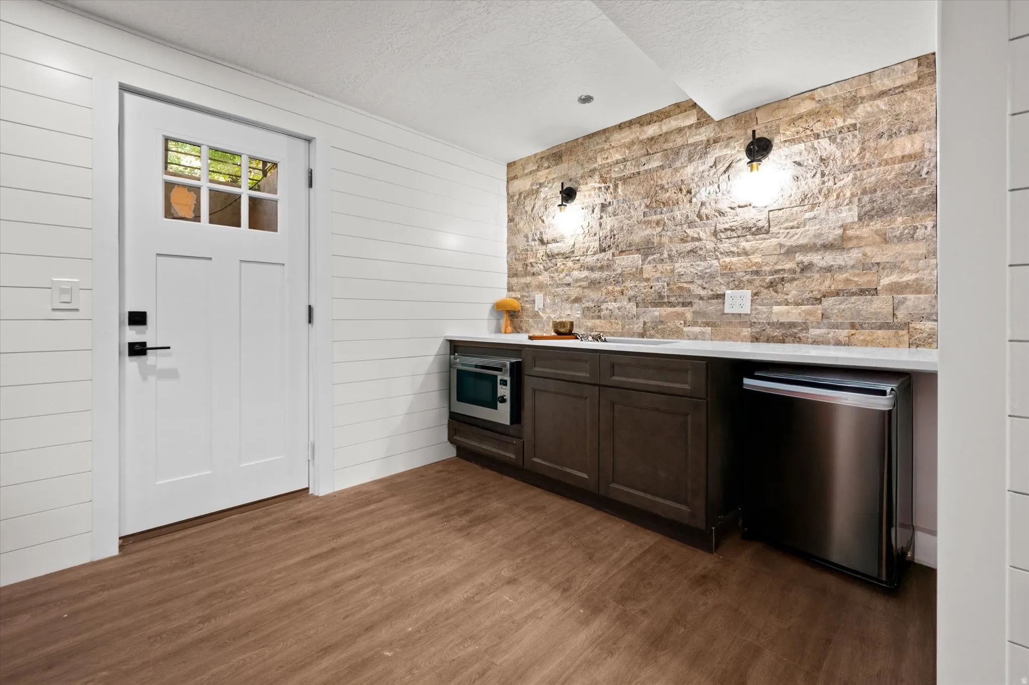 Wet bar featuring an integrated sink, built-in microwave, and undercounter refrigerator