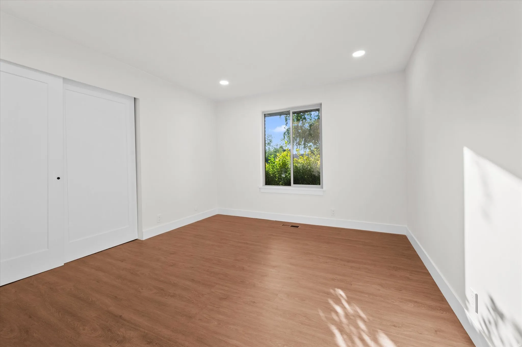 Bright interior space featuring wood-finish flooring, white walls, and recessed lighting