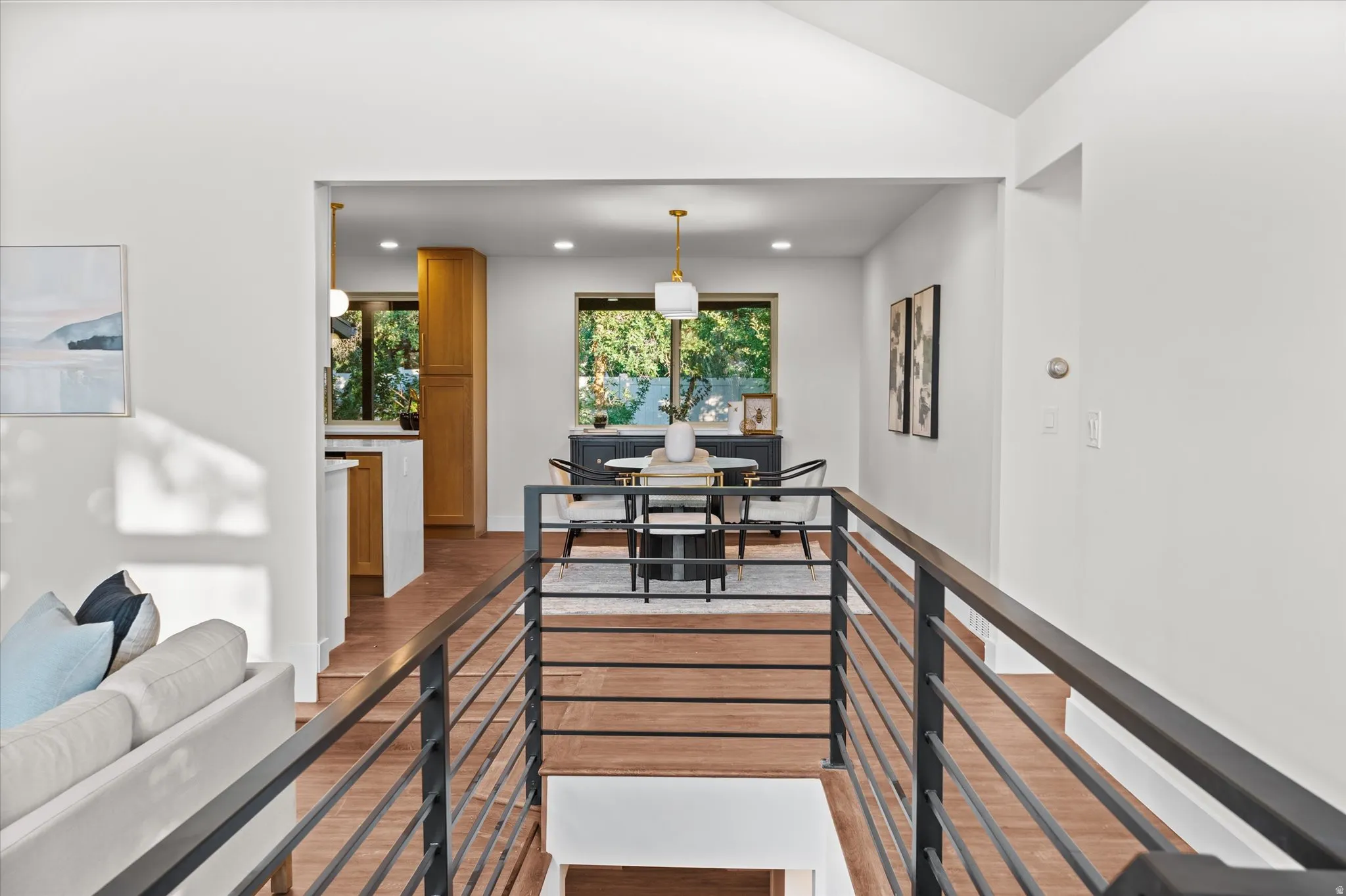 Modern interior featuring wood-finish flooring, a contemporary railing system, and recessed lighting