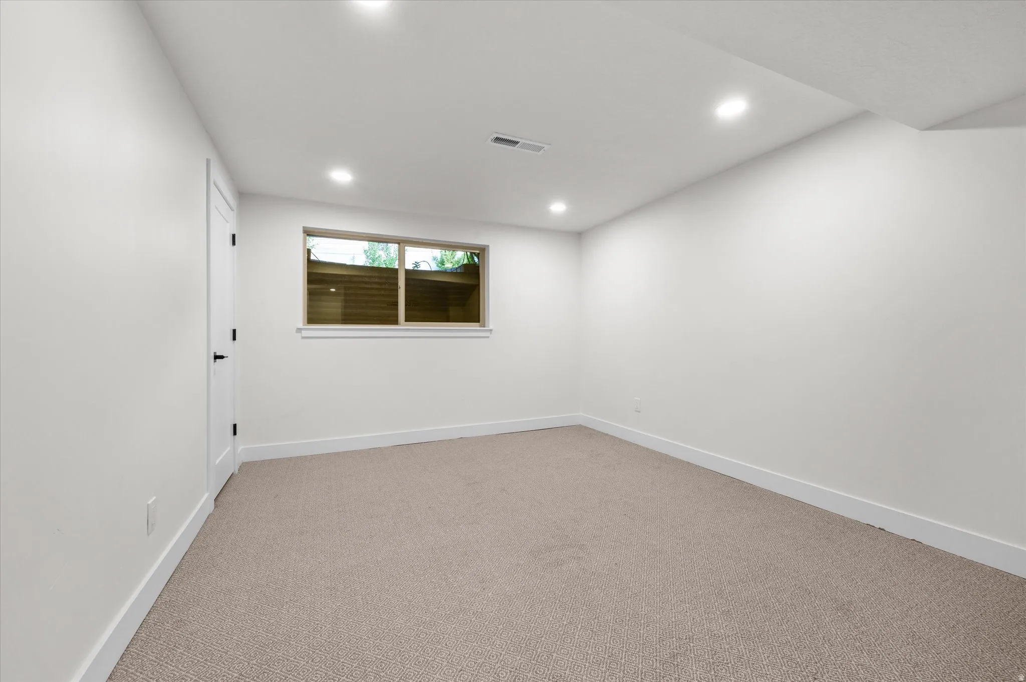 Neutral tone wall finishes with recessed lighting and light-colored carpeting